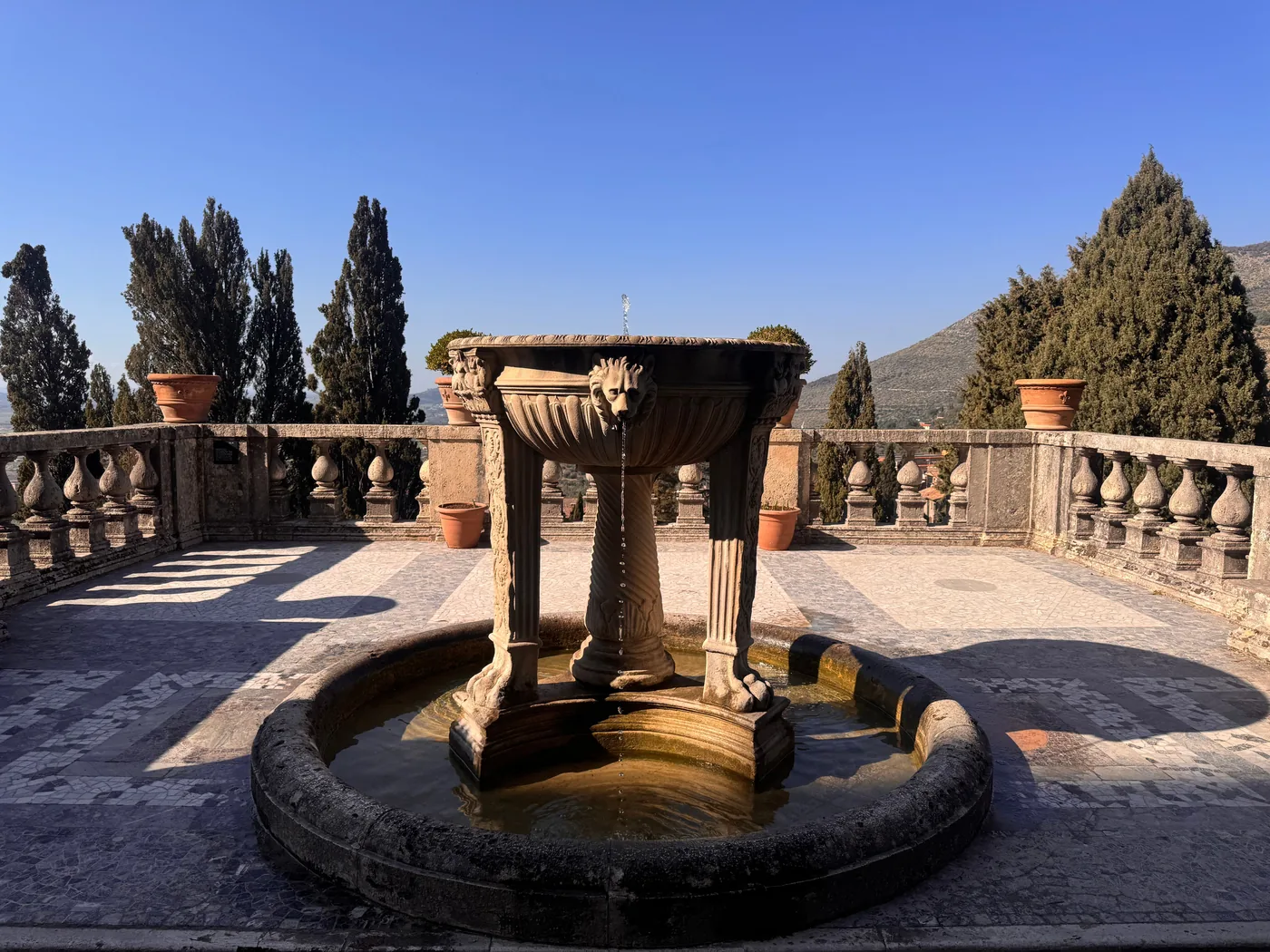 A stone fountain on a balustraded terrace with cypress